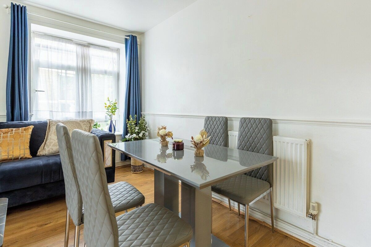 Un comedor con mesa, sillas, sofá y una ventana con cortinas.