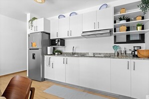 A modern kitchen with white cabinets, stainless steel appliances, and a granite countertop. - Modern 1BR w/2 Pools + Balcony Near Beach & Dining (Punta Cana)