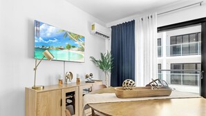Ein modernes Zimmer mit einem Holztisch, einem an der Wand befestigten Fernseher und einem großen Fenster mit Vorhängen.