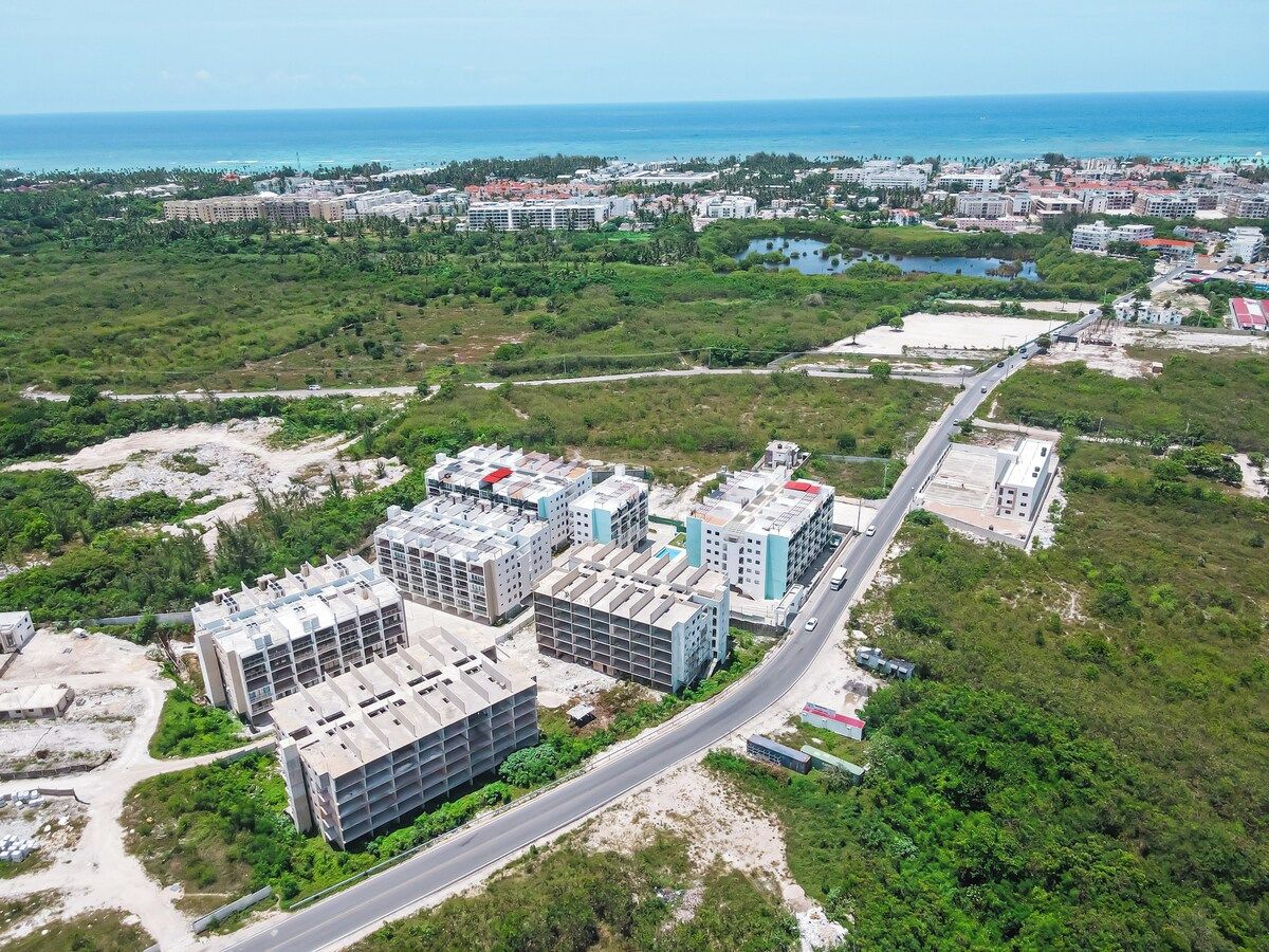 An aerial view of a coastal urban area with modern buildings, roads, and a visible coastline.