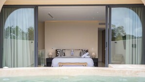 Ein Schlafzimmer mit einem großen Bett, einer Bank und einer Badewanne im Vordergrund.