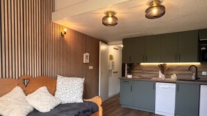 Een moderne slaapkamer met een houten bed, een kleine keuken en een eethoek.