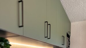 Een moderne keuken met een houten aanrecht, een zwart inductiefornuis en roestvrijstalen apparatuur.