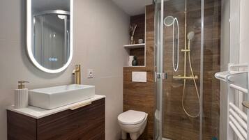 Une salle de bain moderne avec une douche à parois de verre, un lavabo blanc avec un miroir et des meubles en bois.