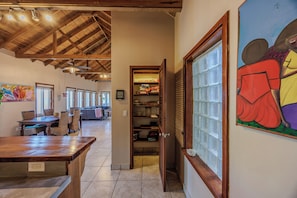 A spacious room with a high ceiling, a dining area with a wooden table and chairs, a kitchen area with a built-in oven, and a large window with a view. - Come hang out for a while! (Sandy Bay)