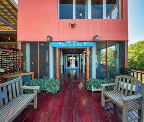 A wooden deck with benches, a sign reading 'Casa Delfin,' and a building with a red facade. - Come hang out for a while! (Sandy Bay)