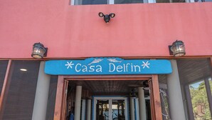 Ein Gebäudeeingang mit einem Schild mit der Aufschrift 'Casa Delfin' und zwei Wandleuchten.
