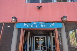 Entrada de um edifício com uma placa indicando 'Casa Delfin' e duas lanternas fixadas na parede.