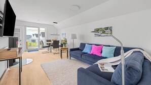 Un salon moderne comprenant un canapé, une table basse, un téléviseur et un coin repas avec des chaises et une table.
