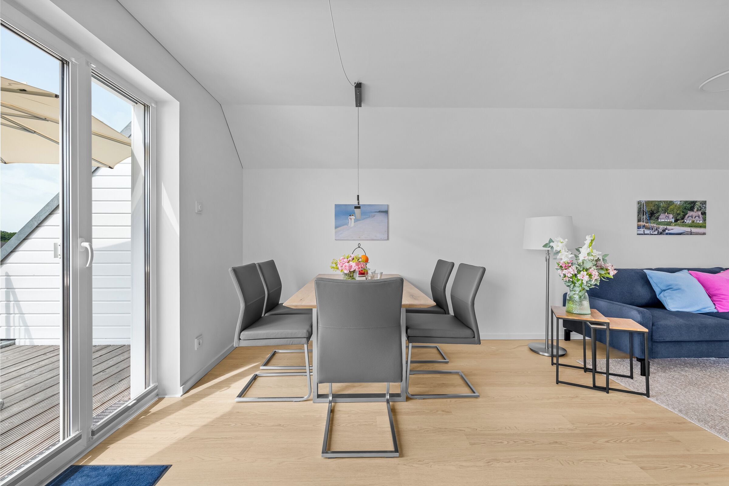 A modern living room with a dining table, grey chairs, a sofa, and a coffee table.