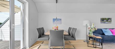 A modern living room with a dining table, grey chairs, a sofa, and a coffee table.