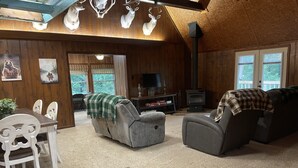 Un intérieur de chalet chaleureux avec une cheminée, des murs en bois, un coin repas et un salon doté de canapés.