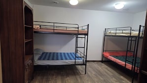 A room with bunk beds, a wooden wardrobe, and a ceiling light.