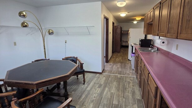 A kitchen with wooden cabinets, a dining table with chairs, and a hallway leading to another room.