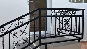 A staircase with ornate black railings leading to a door with a glass panel. - COMFORT AND PEACE OF MIND (Remire-Montjoly)