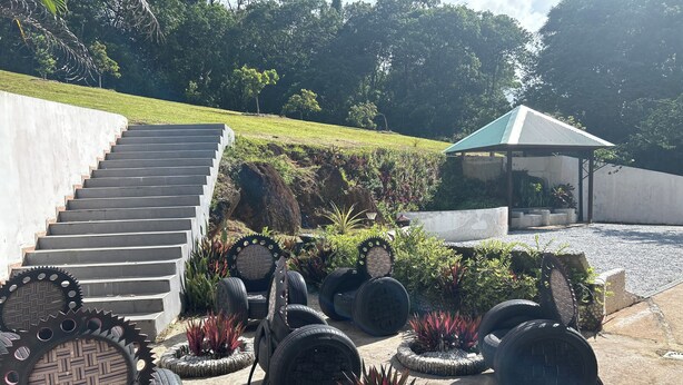 A staircase leading up to a building, surrounded by outdoor seating areas with tire planters and greenery. - COMFORT AND PEACE OF MIND (Remire-Montjoly)
