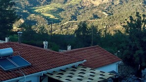 Ein Haus mit rotem Ziegeldach, Solaranlagen und einer Pergola.