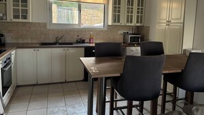 Eine Küche mit weißen Schränken, einem Holztisch und vier Stühlen.