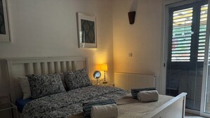 Ein Schlafzimmer mit Bett, Nachttischen, einer Lampe, einem Heizkörper und einer Schiebetür.