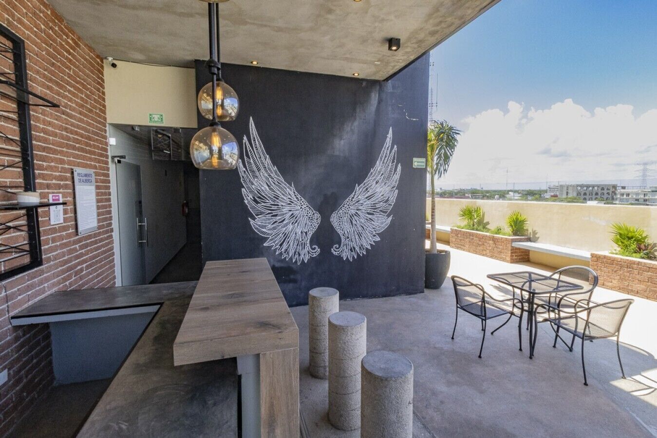 An outdoor patio with a concrete table, chairs, and a wall mural of wings.