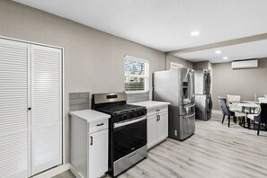 Eine moderne Küche mit Edelstahlgeräten, einem Essbereich mit Tisch und Stühlen sowie einem weißen Schrank.