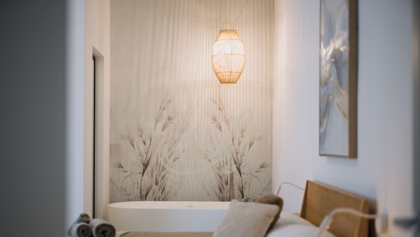 Ein Schlafzimmer mit einem Bett, einer Wandlampe und einem großen Fenster mit Blick auf Bäume.