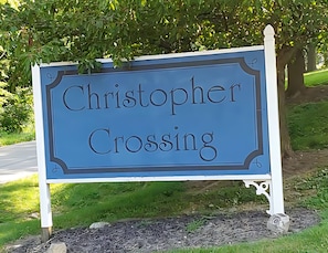 Un letrero con el nombre 'Christopher Crossing' sobre un fondo azul con letras blancas.