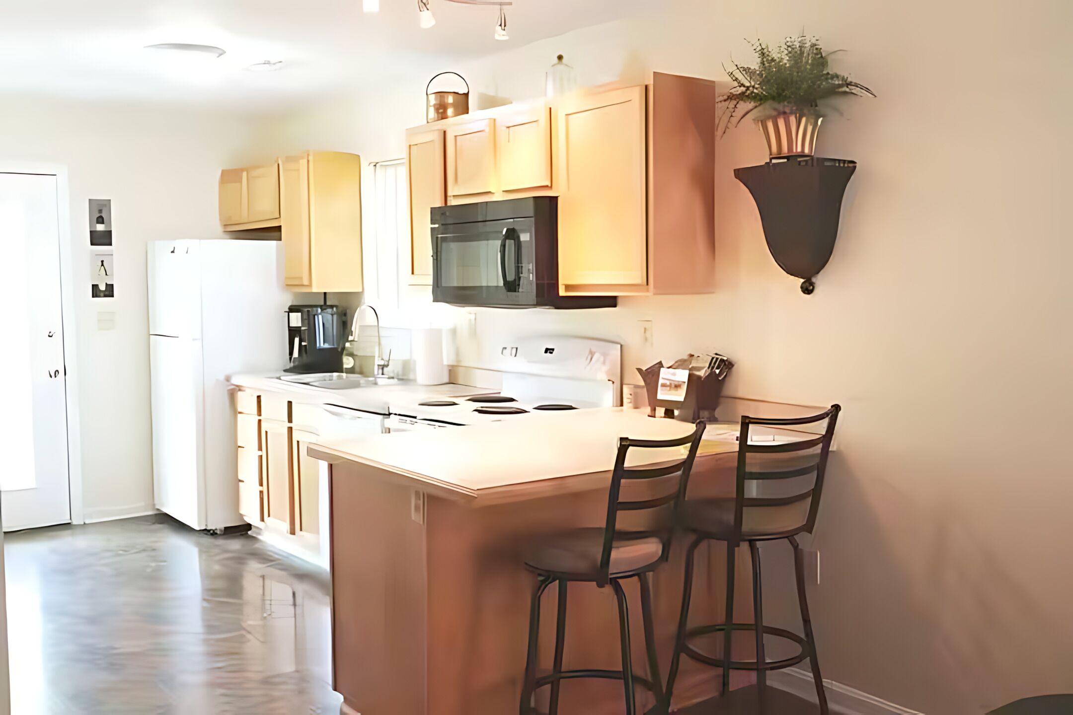 A kitchen with a central island, bar stools, a microwave, and a refrigerator.