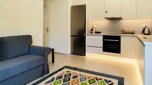 A modern kitchen with white cabinets, a black refrigerator, and a coffee maker. - Hidden Garden Home in Glyfada Center (Glifada)