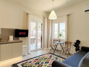 A modern room with a kitchenette, a dining area, and a sofa. - Hidden Garden Home in Glyfada Center (Glifada)