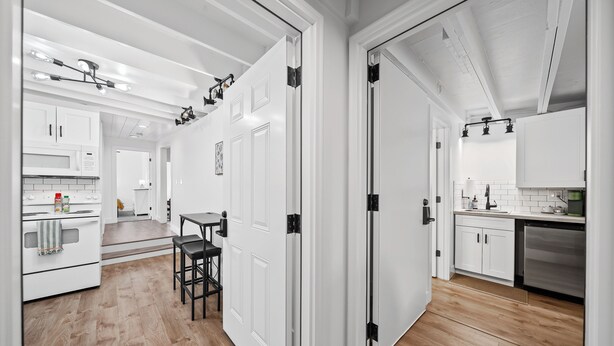 Une cuisine moderne avec des meubles blancs, un plancher en bois et un coin repas comprenant une table et des chaises.