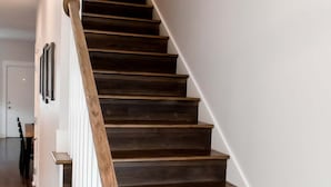 A wooden staircase with white railings and a handrail, leading to an upper floor. - Brand New 2 Bedroom Conveniently Located Two Blocks From F&M Bank Arena (Clarksville)
