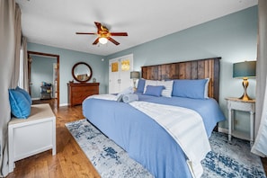 A bedroom with a large bed, a ceiling fan, a dresser, a mirror, and a bedside table with a lamp. - Horse Haven 3br/2ba at Liberty Star Farms (Clarksville)