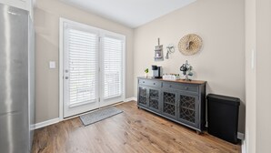 A kitchen with a refrigerator, double doors, a coffee station, and a trash bin. - Cottage With Community Pool (Clarksville)