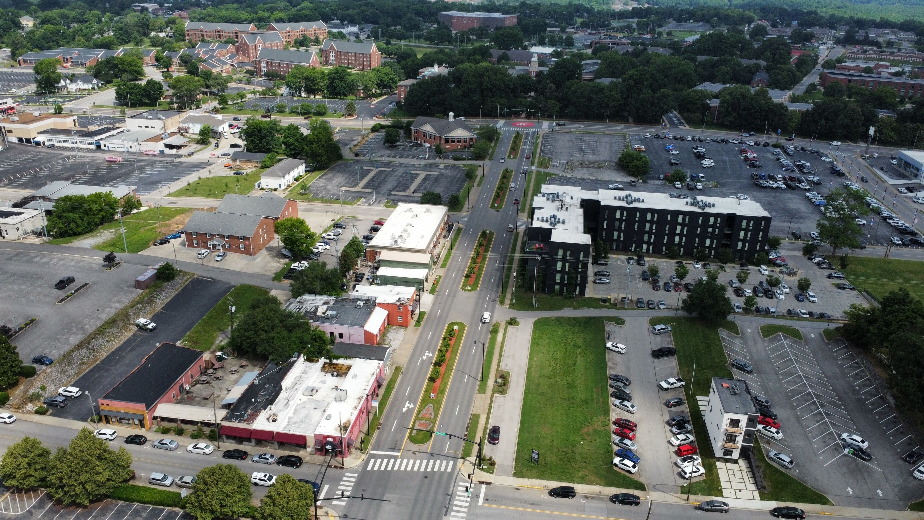 Vue aérienne d’une zone commerciale avec des parkings, des immeubles et des routes.