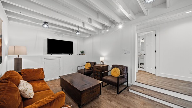 Un salon moderne comprenant un canapé, une table basse et des fauteuils, un téléviseur à écran plat et un escalier menant à un autre niveau.