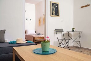A room with a bed, a small table with a potted plant, a folding chair, and a wall-mounted picture. - The Yellow Donkey Koumeika Traditional Stay Samos (Samos)
