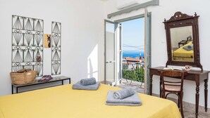 Une chambre d’hôtel comprenant un lit, un bureau avec un miroir, une fenêtre donnant sur un paysage agréable et un mur orné d’œuvres d’art en métal.