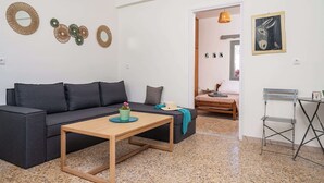 Un salon moderne avec un canapé d’angle, une table basse en bois et des œuvres d’art décoratives accrochées au mur.