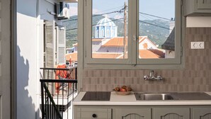 Une cuisine avec une fenêtre donnant sur un bâtiment à coupole bleue, un évier et un saladier rempli de fruits.