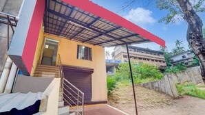 A two-story building with a red roof, a staircase, and a gated entrance. - Premium Kunnamangalam Near Bus Stand (Kozhikode)