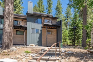 A modern two-story building with a balcony, surrounded by trees. - Alpenglow Loft | Palisades Adventure Basecamp (Olympic Valley)