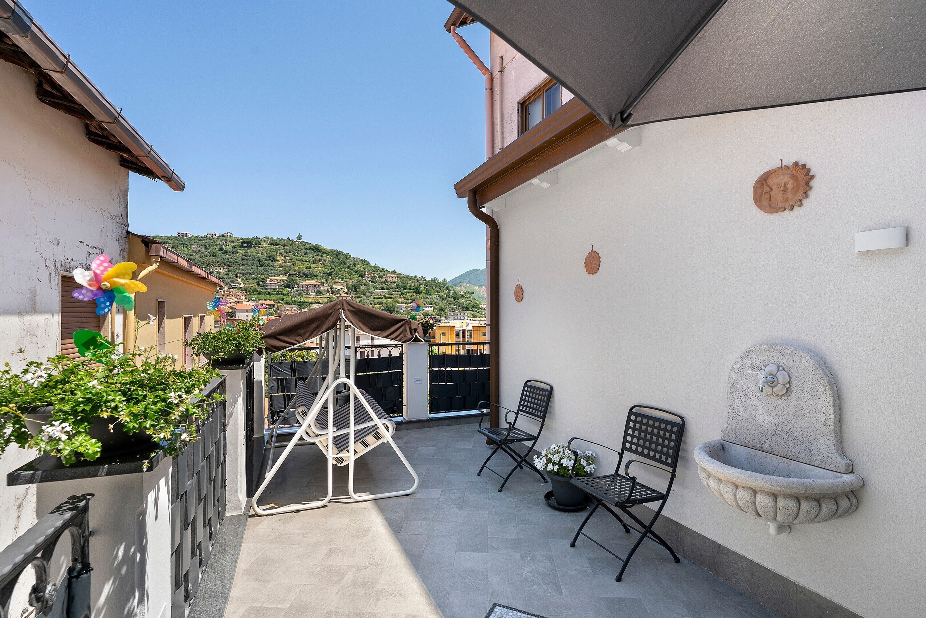 A balcony with a swing chair, a small table, and a wall-mounted planter.