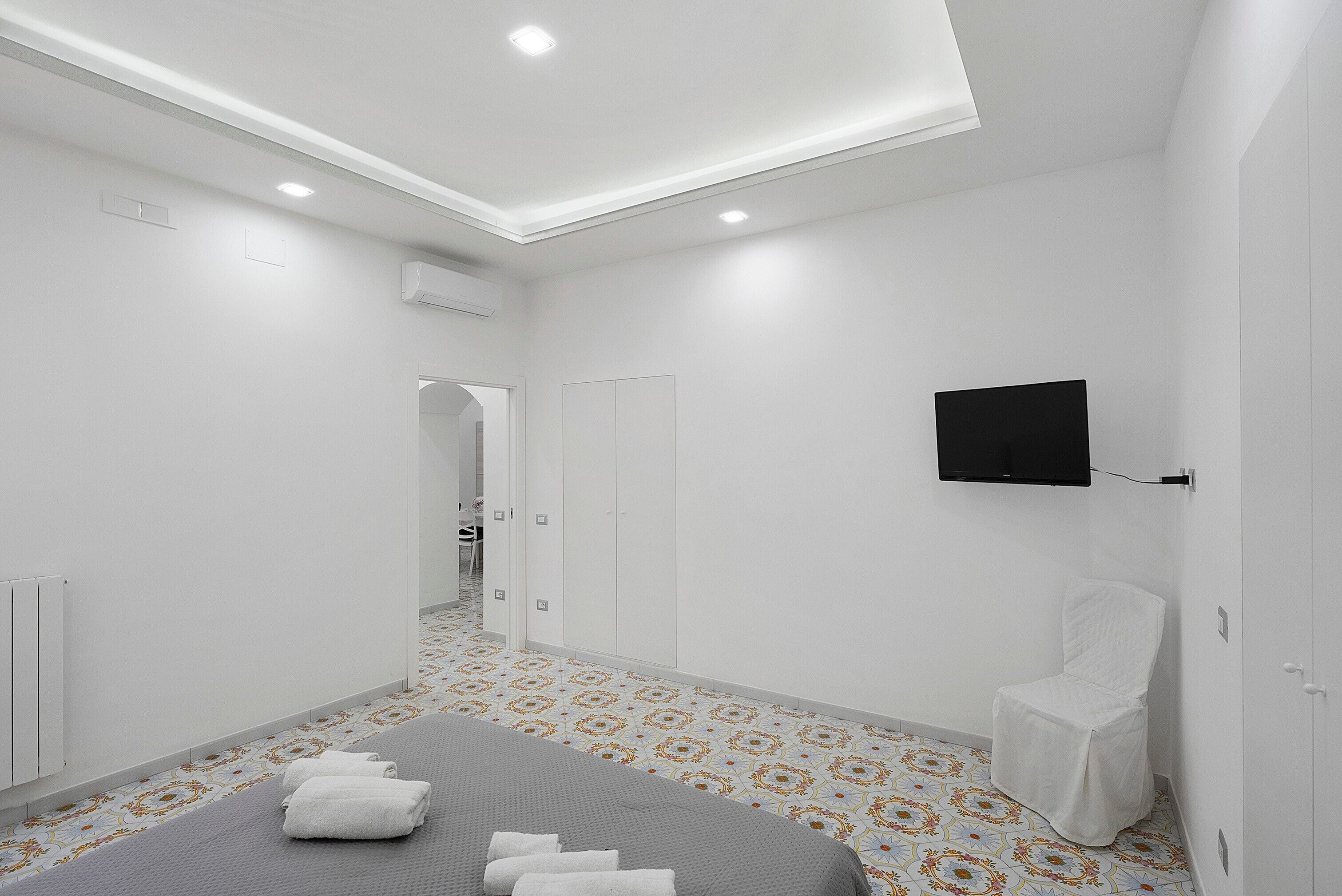 Ein Hotelzimmer mit Bett, einem an der Wand befestigten Fernseher und einem Badezimmer mit Handtuchhalter.