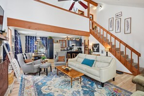 A spacious living area with a sofa, armchairs, a coffee table, and a staircase. - Pocono Lake House - Short Walk to All Amenities! (Albrightsville)