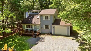 A two-story house with a garage, surrounded by trees. - Pocono Lake House - Short Walk to All Amenities! (Albrightsville)