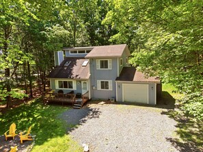 A two-story house with a garage, surrounded by trees. - Pocono Lake House - Short Walk to All Amenities! (Albrightsville)