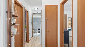 A hallway with wooden doors, a visible door labeled 'CAMEROOM,' and a glimpse of a dining area in the background. - Pocono Lake House - Short Walk to All Amenities! (Albrightsville)