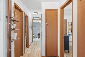 A hallway with wooden doors, a visible door labeled 'CAMEROOM,' and a glimpse of a dining area in the background. - Pocono Lake House - Short Walk to All Amenities! (Albrightsville)