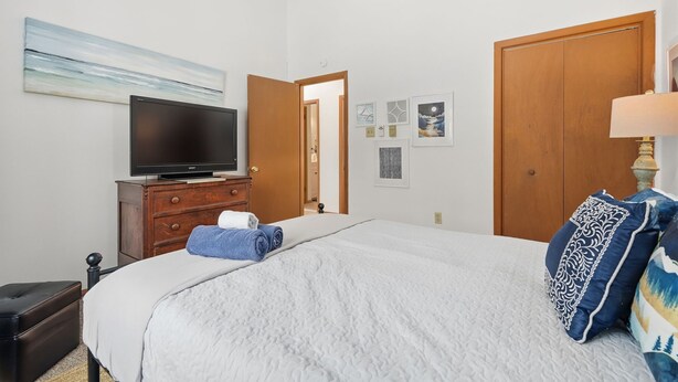 A bedroom with a bed, a television on a dresser, a wooden door, and a painting on the wall. - Pocono Lake House - Short Walk to All Amenities! (Albrightsville)